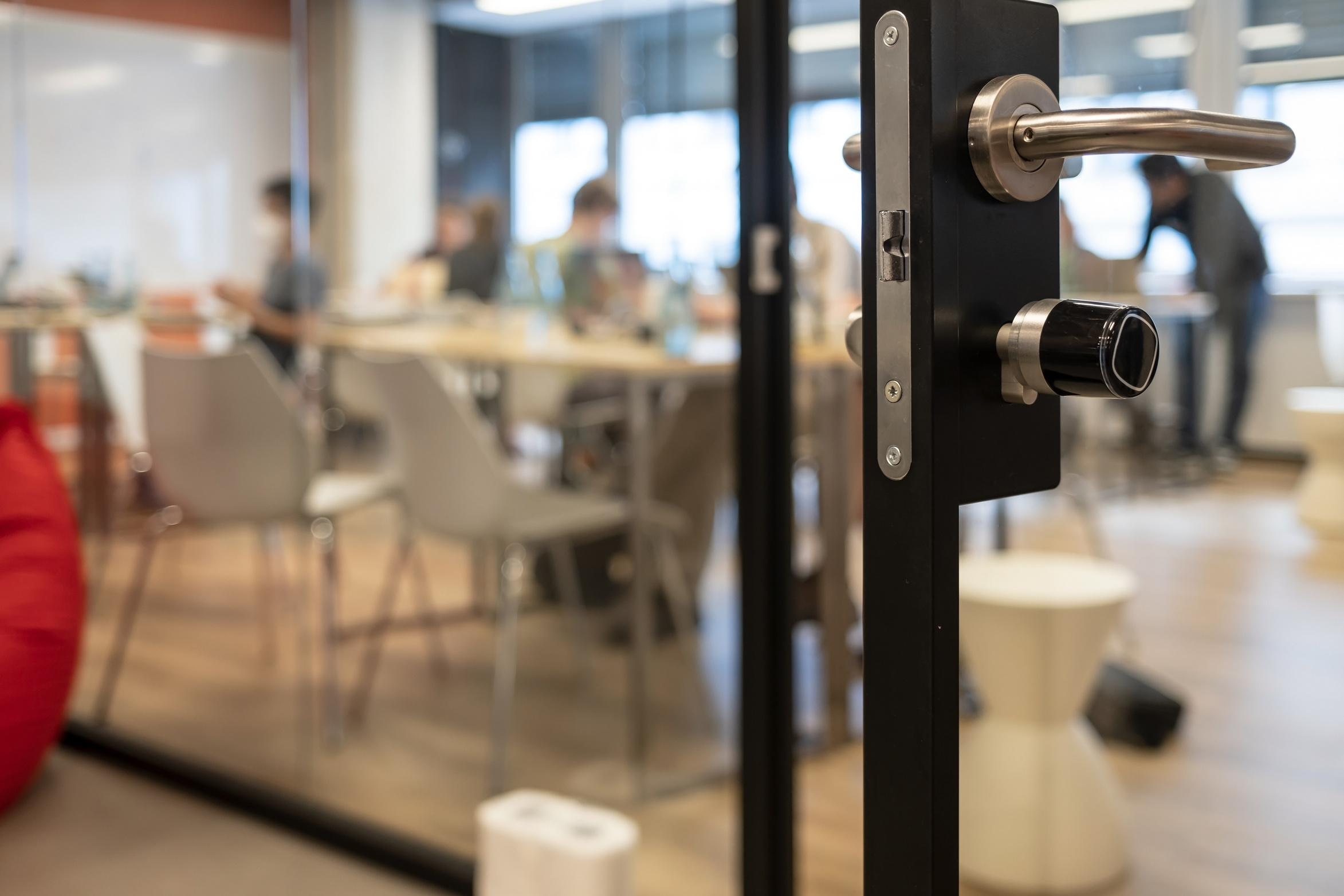 Open door to a coworking space, blurred silhouettes of people during a hackathon